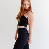 Alt text: "A woman is modeling Raeya Fit's best-selling Rae Butter Collection black leggings, renowned for their 5-star reviews. These high-waisted leggings feature a 28" inseam to fit all heights, a Glute-Curve back seam to enhance the booty, and no front or side seams for a sleek silhouette. The double-lined hip band ensures they stay in place during workouts. Made from ultra-soft, comfortable fabric, these leggings are perfect for both exercise and everyday wear."